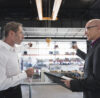 Two businessmen with clipboard talking on factory shop floor